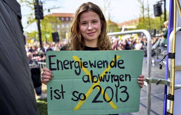 Bild der Klimaaktivistin Luisa Neubauer bei der Demonstration in Berlin mit dem Plakat in der Hand mit der Aufschrift "Energiewende abwürgen ist so wie 2013"