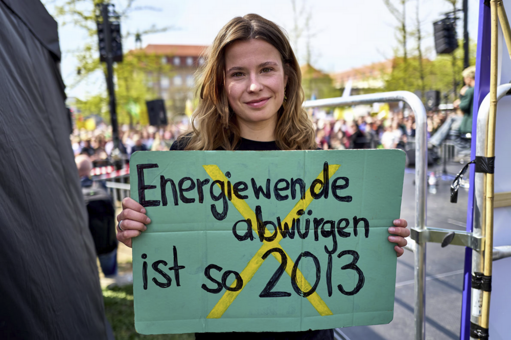 Bild der Klimaaktivistin Luisa Neubauer bei der Demonstration in Berlin mit dem Plakat in der Hand mit der Aufschrift "Energiewende abwürgen ist so wie 2013"