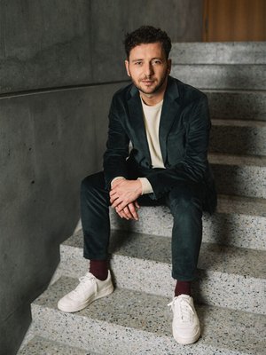Ein Bild von Felix Banaszak wie er auf einer Treppe sitzt
